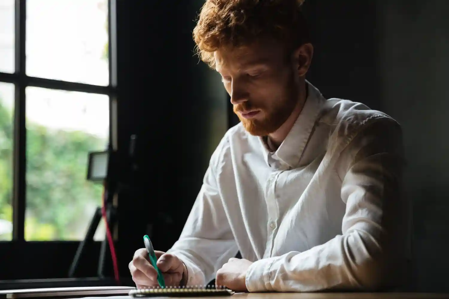 A young man writing quietly at a desk